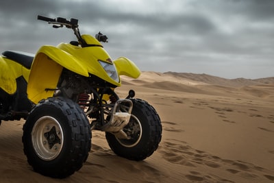 黄色和黑色ATV在沙漠的沙丘
